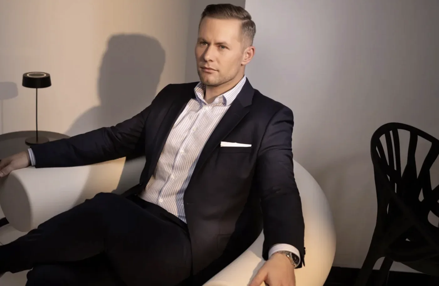 Business-Porträt eines Unternehmers im blauen Anzug auf weißem Sessel Business-Porträt eines Unternehmers im blauen Anzug auf weißem Sessel